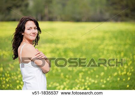 Stock Photo - Pretty brunette woman in countryside smiling at camera. Fotosearch
