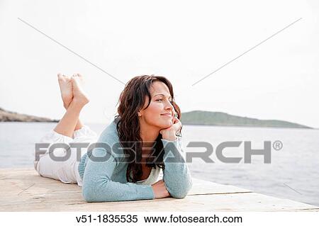 Pretty brunette woman lying on a seaside Pier View Large Photo Image Stock Photography - Pretty brunette woman lying on a seaside Pier. Fotosearch
