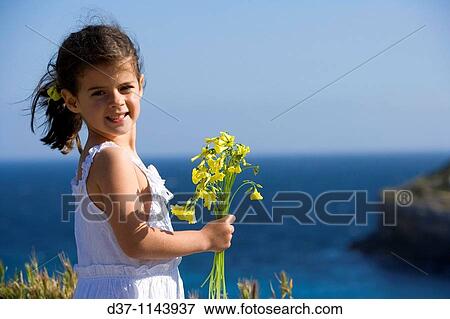 Pretty caucasian girl holding a bunch of flowers in front of the sea View Large Photo Image Stock Photo - Pretty caucasian girl holding a bunch of flowers in front of the sea. Fotosearch