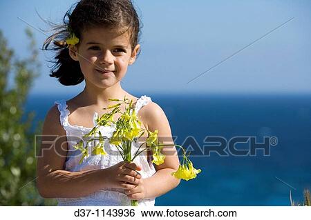 Pretty caucasian girl holding a bunch of flowers in front of the sea View Large Photo Image Stock Photograph - Pretty caucasian girl holding a bunch of flowers in front of the sea. Fotosearch