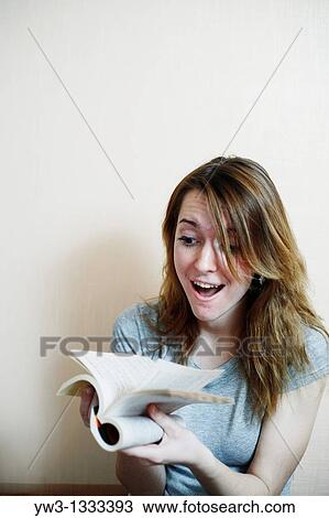 Stock Image - pretty girl against light wall with book. Fotosearch
