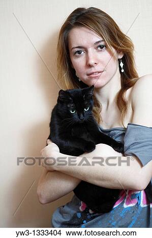 Picture - pretty girl against light wall with black cat. Fotosearch