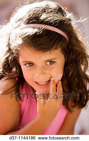 Stock Photograph - Pretty girl applying facial cream. Fotosearch