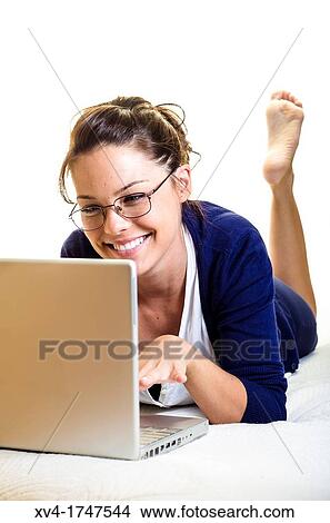 Picture - Pretty girl chatting on notebook in the bedroom. Fotosearch