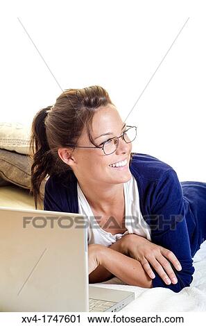 Stock Image - Pretty girl chatting on notebook in the bedroom. Fotosearch