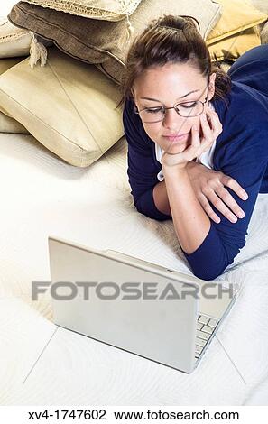 Stock Image - Pretty girl chatting on notebook in the bedroom. Fotosearch