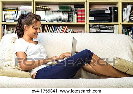 Stock Image - Pretty girl chatting on notebook in the bedroom. Fotosearch