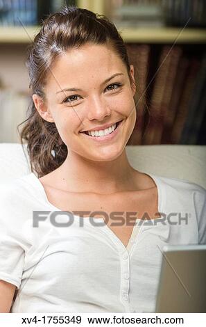 Stock Photo - Pretty girl chatting on notebook in the bedroom. Fotosearch