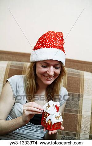pretty girl in the Christmas hat on sofa with little red xmas house in hands View Large Photo Image Picture - pretty girl in the Christmas hat on sofa with little red xmas house in hands. Fotosearch