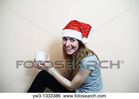 pretty girl in the Christmas hat against light wall with cup of tea or coffee View Large Photo Image Stock Photograph - pretty girl in the Christmas hat against light wall with cup of tea or coffee. Fotosearch
