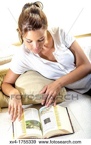 Stock Photo - Pretty girl reading book in the bedroom. Fotosearch