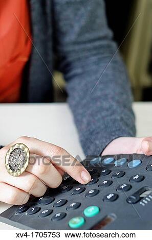 Stock Image - Pretty girl take notes and calculator tasks. Fotosearch
