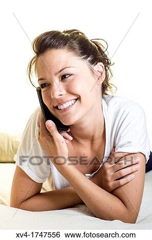 Stock Photograph - Pretty girl talk with mobile phone in the bedroom. Fotosearch