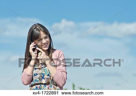 Stock Image - Pretty girl with cell phone in outdoors. Fotosearch