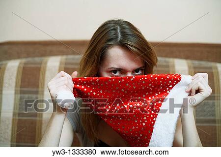 Stock Image - pretty girl with the Christmas hat in hands on sofa. Fotosearch