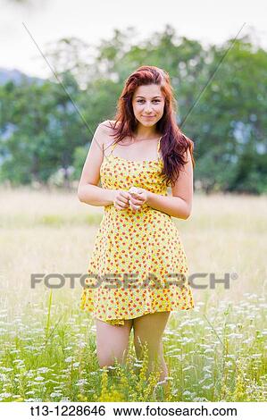Pretty in a flowery dress young woman in a field View Large Photo Image Stock Photograph - Pretty in a flowery dress young woman in a field. Fotosearch