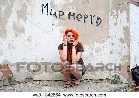 Picture - pretty redhead girl against obsolete wall. Fotosearch