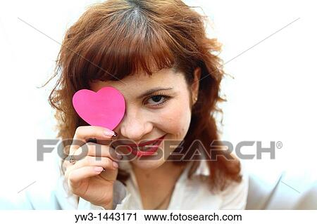 Stock Image - Pretty redhead young woman portrait with heart indoors. Fotosearch