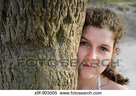 Pretty teen girl peers from behind a palm tree on Hunting Island in South Carolina, USA in April Hunting Island is well known for its five mile white sand beach View Large Photo Image Stock Photography - Pretty teen girl peers from behind a palm tree on Hunting Island in South Carolina, USA in April Hunting Island is well known for its five mile white sand beach. Fotosearch