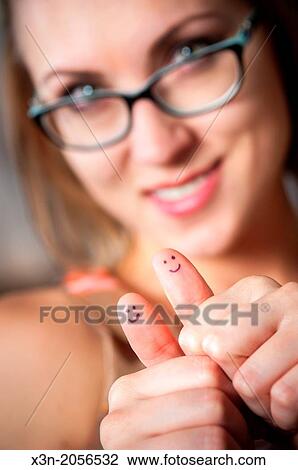 Stock Image - Pretty woman with smiles on thumbs giving thumbs up.. Fotosearch
