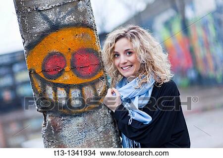 Pretty young woman and odd smiling painted face on the column View Large Photo Image Picture - Pretty young woman and odd smiling painted face on the column. Fotosearch