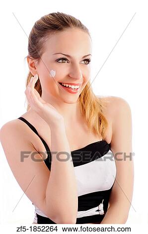 Picture - Pretty young woman applying face cream. Fotosearch