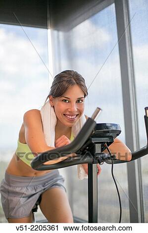 Pretty young woman doing spinning bike in fitness center and smiling at camera View Large Photo Image Stock Image - Pretty young woman doing spinning bike in fitness center and smiling at camera. Fotosearch