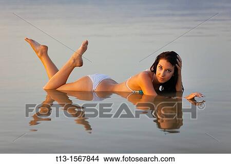 Picture - Pretty young woman in lying in very shallow water. Fotosearch