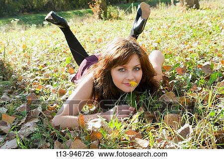 Pretty young woman is lying on grass with a single yellow flower in hand View Large Photo Image Stock Photograph - Pretty young woman is lying on grass with a single yellow flower in hand. Fotosearch