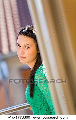 Stock Image - Pretty young woman is peeking behind a corner. Fotosearch