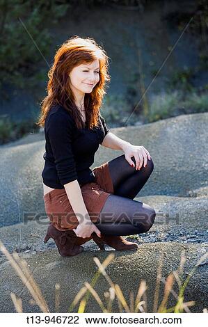 Pretty young woman is squatting and winking on one eye View Large Photo Image Stock Image - Pretty young woman is squatting and winking on one eye. Fotosearch