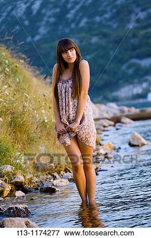 Stock Photo - Pretty young woman is walking on the coastline. Fotosearch