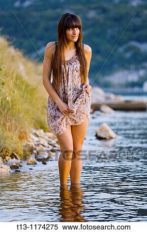 Stock Photography - Pretty young woman is walking on the coastline. Fotosearch