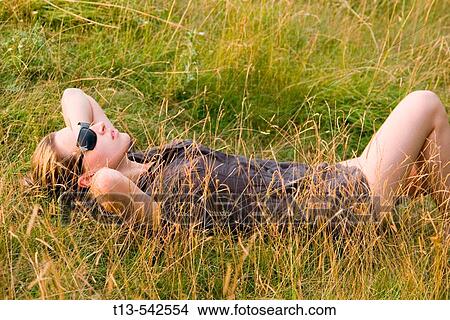 Pretty young woman lying and resting in grass View Large Photo Image Picture - Pretty young woman lying and resting in grass. Fotosearch