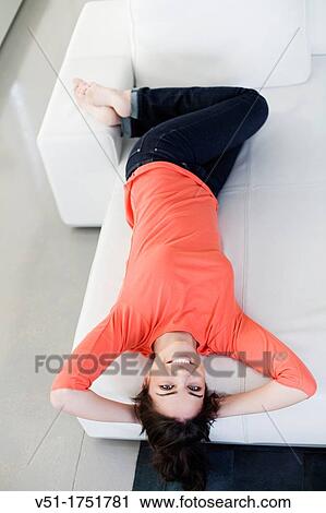 Pretty young woman lying at the sofa smiling at camera View Large Photo Image Stock Image - Pretty young woman lying at the sofa smiling at camera. Fotosearch