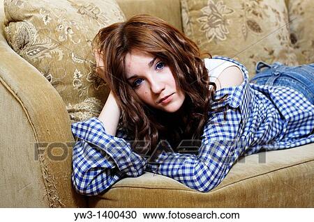 Pretty young woman lying on sofa, looking at camera View Large Photo Image Stock Image - Pretty young woman lying on sofa, looking at camera. Fotosearch