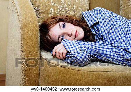 Pretty young woman lying on sofa, looking at camera View Large Photo Image Stock Image - Pretty young woman lying on sofa, looking at camera. Fotosearch
