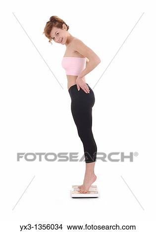 Pretty young woman on scale, isolated on white background View Large Photo Image Picture - Pretty young woman on scale, isolated on white background. Fotosearch