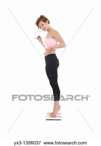 Pretty young woman on scale, isolated on white background View Large Photo Image Stock Photo - Pretty young woman on scale, isolated on white background. Fotosearch