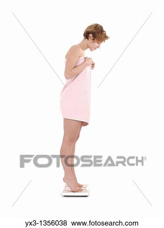 Stock Photo - Pretty young woman on scale, isolated on white background. Fotosearch