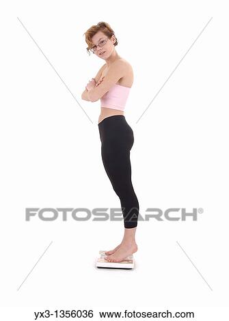 Stock Photograph - Pretty young woman on scale, isolated on white background. Fotosearch