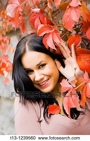 Stock Image - Pretty young woman portrait in Red Autumn leaves. Fotosearch