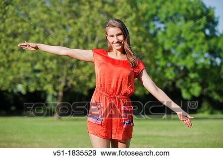 Stock Photo - Pretty young woman relaxing in park smiling at camera. Fotosearch