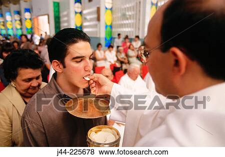 Priest giving the Communion during mass View Large Photo Image Stock Photo - Priest giving the Communion during mass. Fotosearch