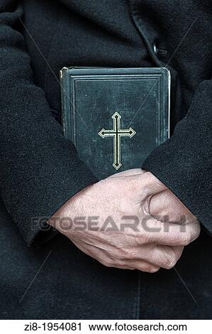 Stock Image - Priest holds the holy bible. Fotosearch