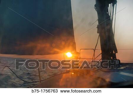 Stock Image - Primer plano de cubierta de un barco velero navegando al atardecer entre Menorca y Mallorca, mar Mediterraneo, Baleares, Espaa, Close-up of cover of a sailboat sailing on a sunset between Menorca and Mallorca, Mediterranean Sea, Balearic, Spain. Fotosearch