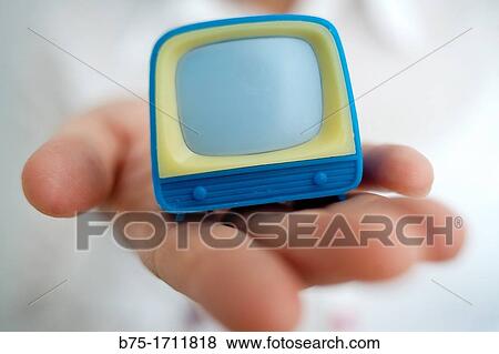 Stock Photo - primer plano de mano mostrando un televisor de juguete, close-up of hand showing a TV toy,. Fotosearch