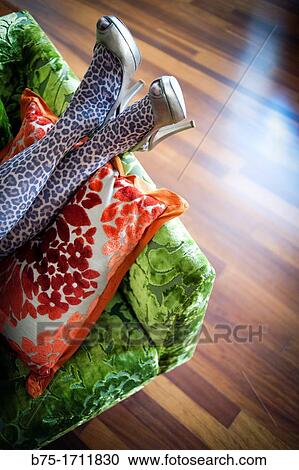 Stock Image - Primer plano de piernas de mujer apoyadas en el sofB descansando, Closeup of female legs resting on the sofa. Fotosearch