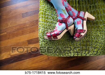 Stock Photography - primer plano de pies de mujer con sandalias rojas y medias de colores en postura de descanso, closeup of woman feet with red sandals and colorful tights in rest position. Fotosearch