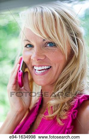 Profile of a 35 year old blond woman talking on a cell phone smiling at the camera View Large Photo Image Stock Photo - Profile of a 35 year old blond woman talking on a cell phone smiling at the camera. Fotosearch
